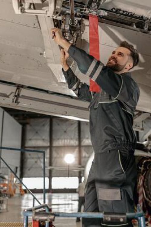 cheerful-male-mechanic-repairing-aircraft-at-repair-station-photo